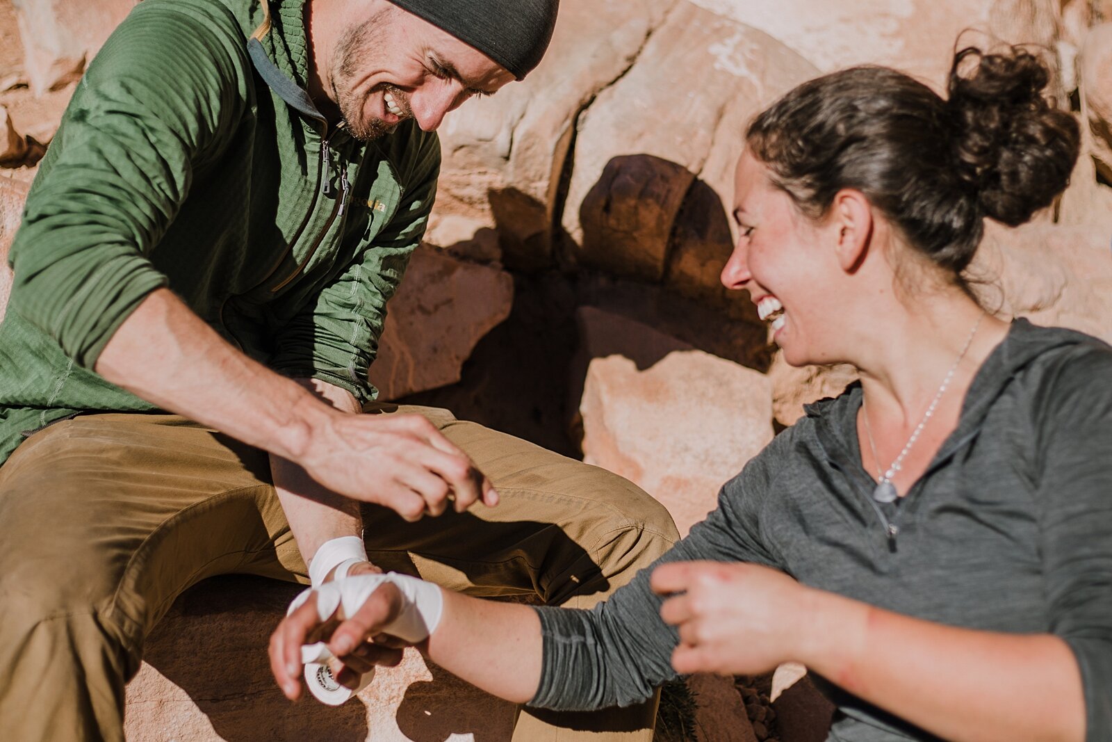 couple making tape gloves in indian creek near monticello utah, indian creek climbing area, canyonlands national park, moab utah engagements, crack climbing moab utah
