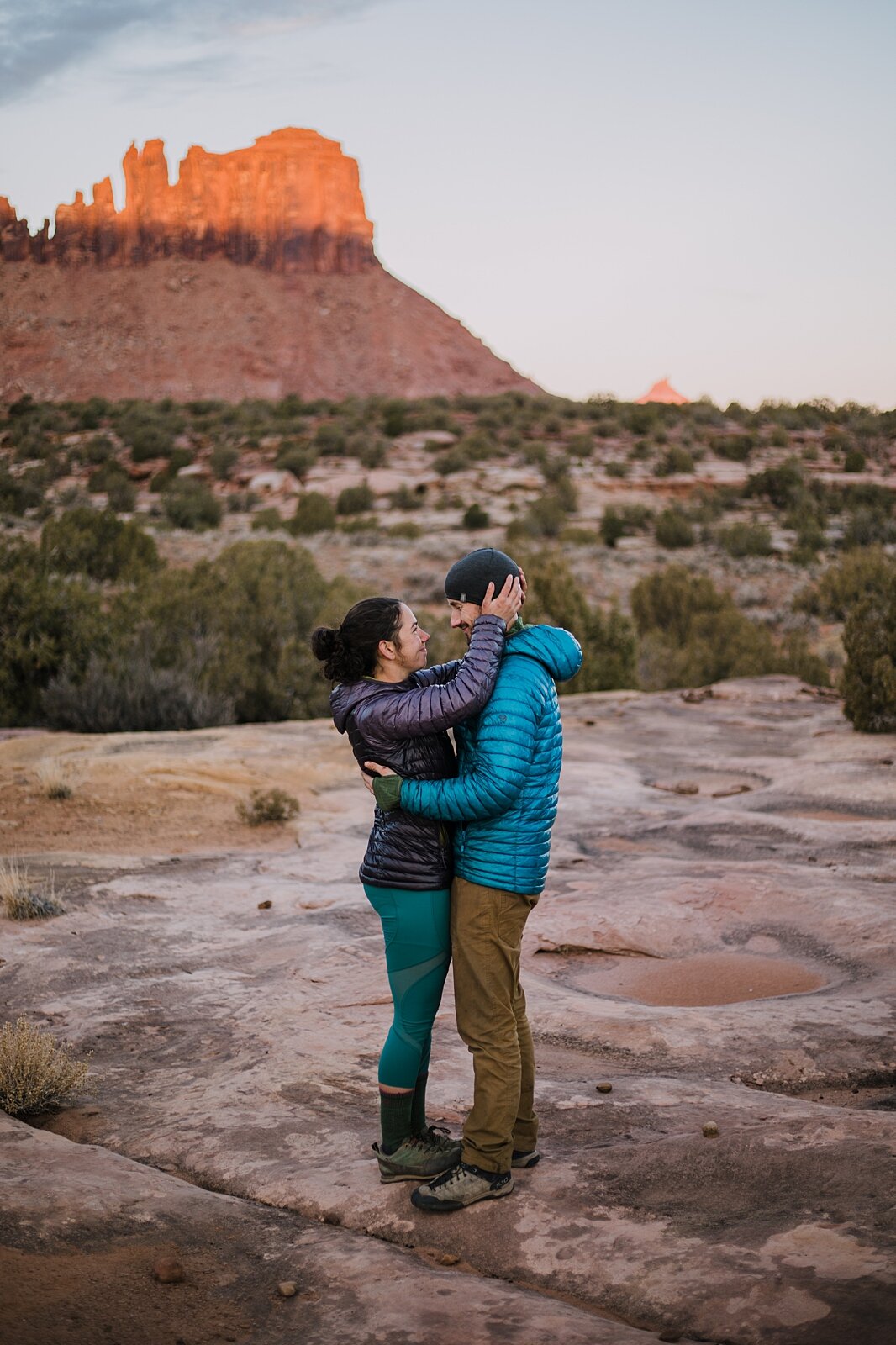 couple canoodling in indian creek, indian creek climbing area, canyonlands national park, moab utah engagements, sunrise in moab utah