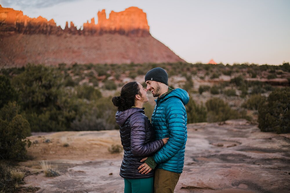 couple cuddling in indian creek, indian creek climbing area, canyonlands national park, moab utah engagements, sunrise in moab utah