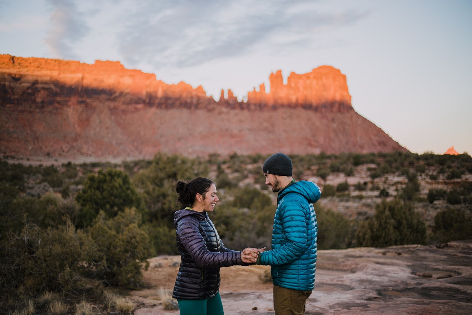 couple holding hands in indian creek, indian creek climbing area, canyonlands national park, moab utah engagements, sunrise in moab utah
