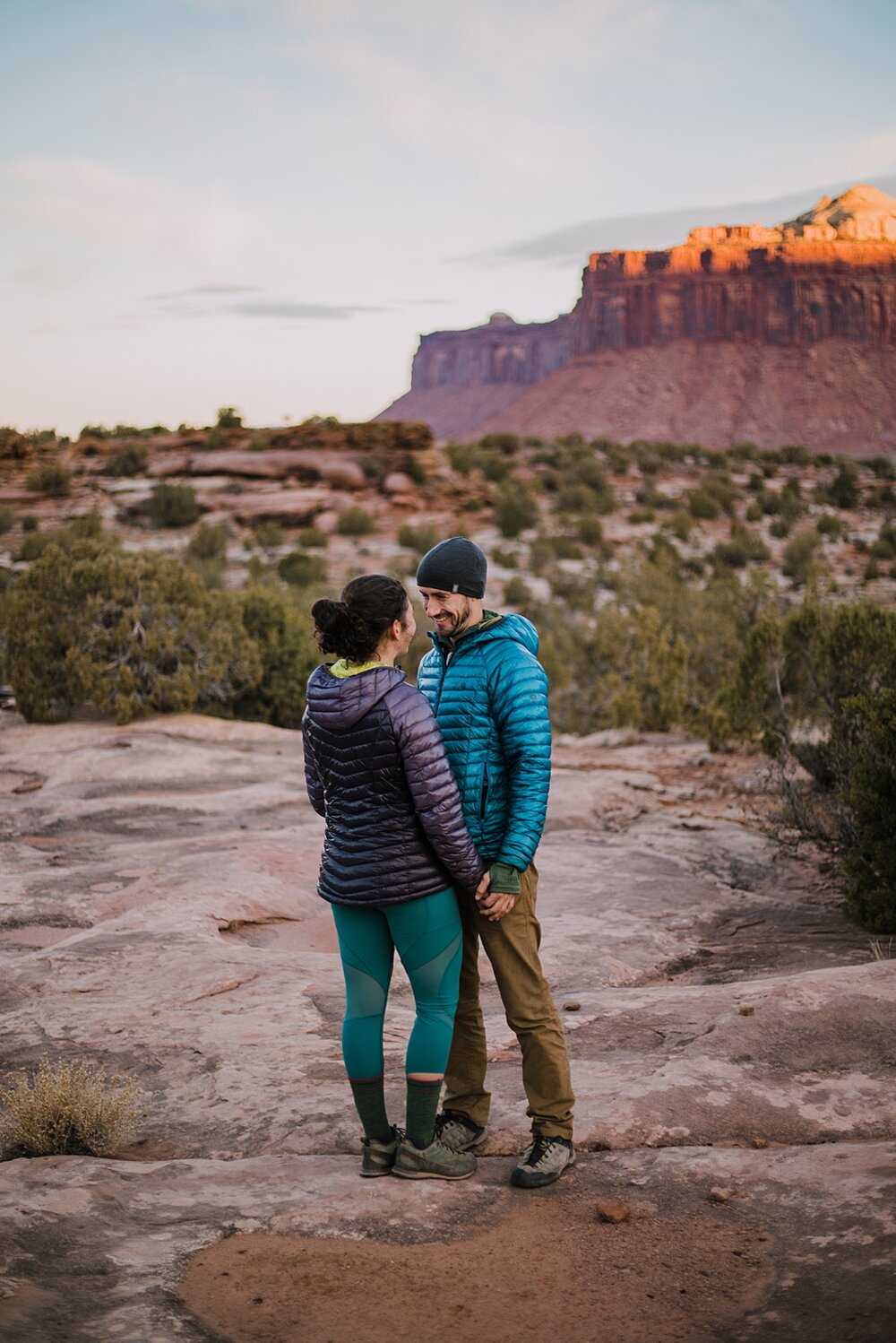 couple hiking through indian creek near monticello utah, indian creek climbing area, canyonlands national park, moab utah engagements, sunrise in moab utah