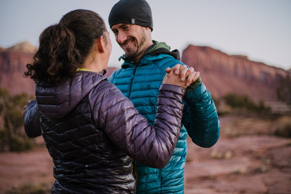 couple hiking during sunrise alpine glow at indian creek, indian creek climbing area, canyonlands national park, moab utah engagements, sunrise in moab utah