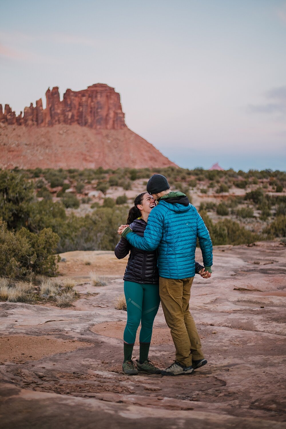 couple hiking holding hands through indian creek, indian creek climbing area, canyonlands national park, moab utah engagements, sunrise in moab utah