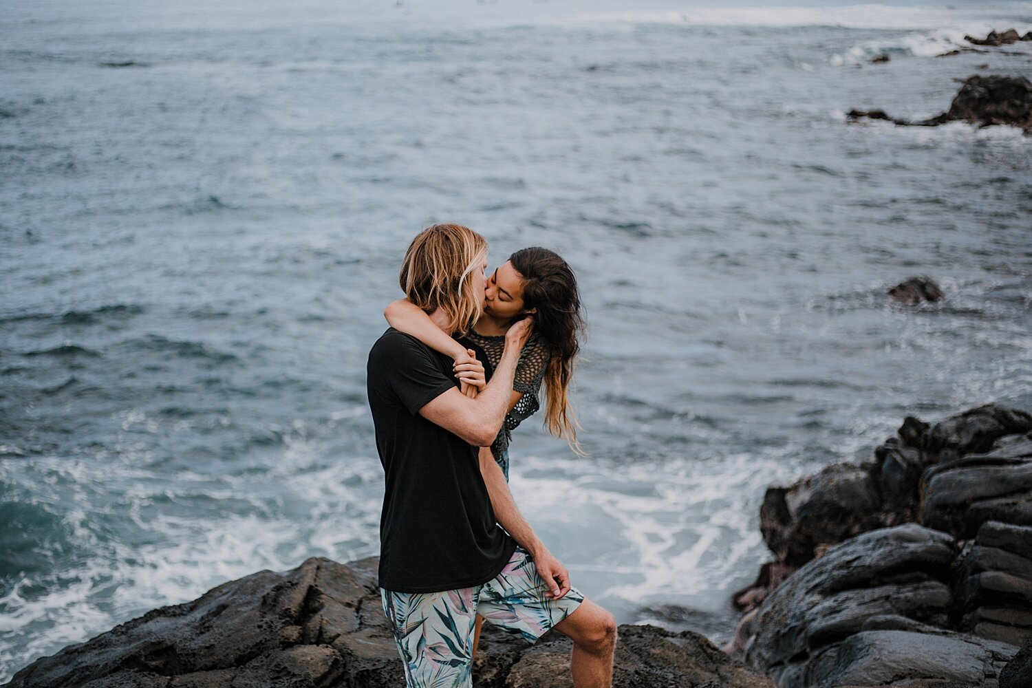 couple kissing on lava rocks on ho'okipa beach, couple hiking ho'okipa, maui hawaii photographer, maui hawaii surfing, surfing at ho'okipa beach, ho'okipa beach engagements, motorcycle engagements