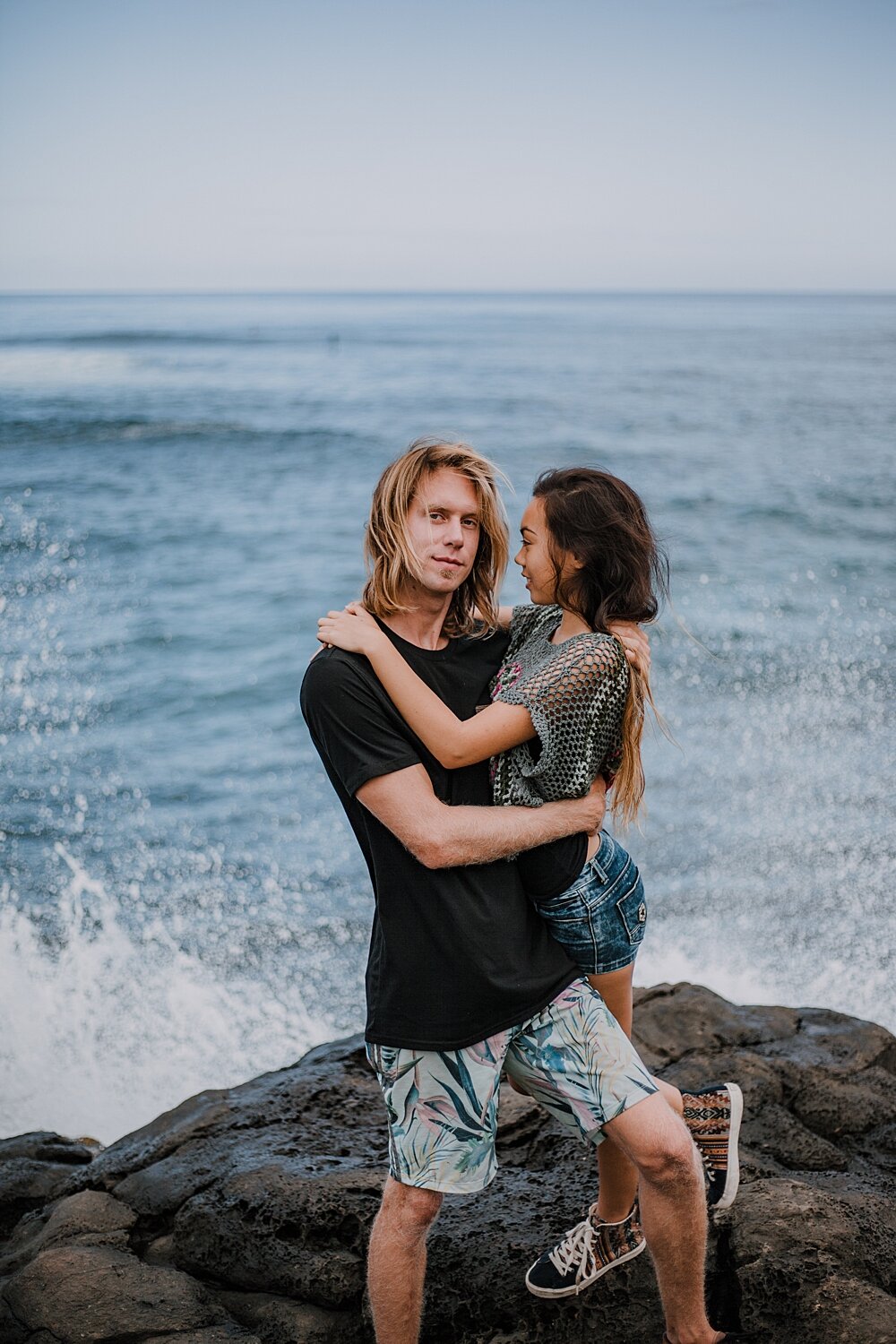 couple standing on lava rocks on ho'okipa beach, couple hiking ho'okipa, maui hawaii photographer, maui hawaii surfing, surfing at ho'okipa beach, ho'okipa beach engagements, motorcycle engagements