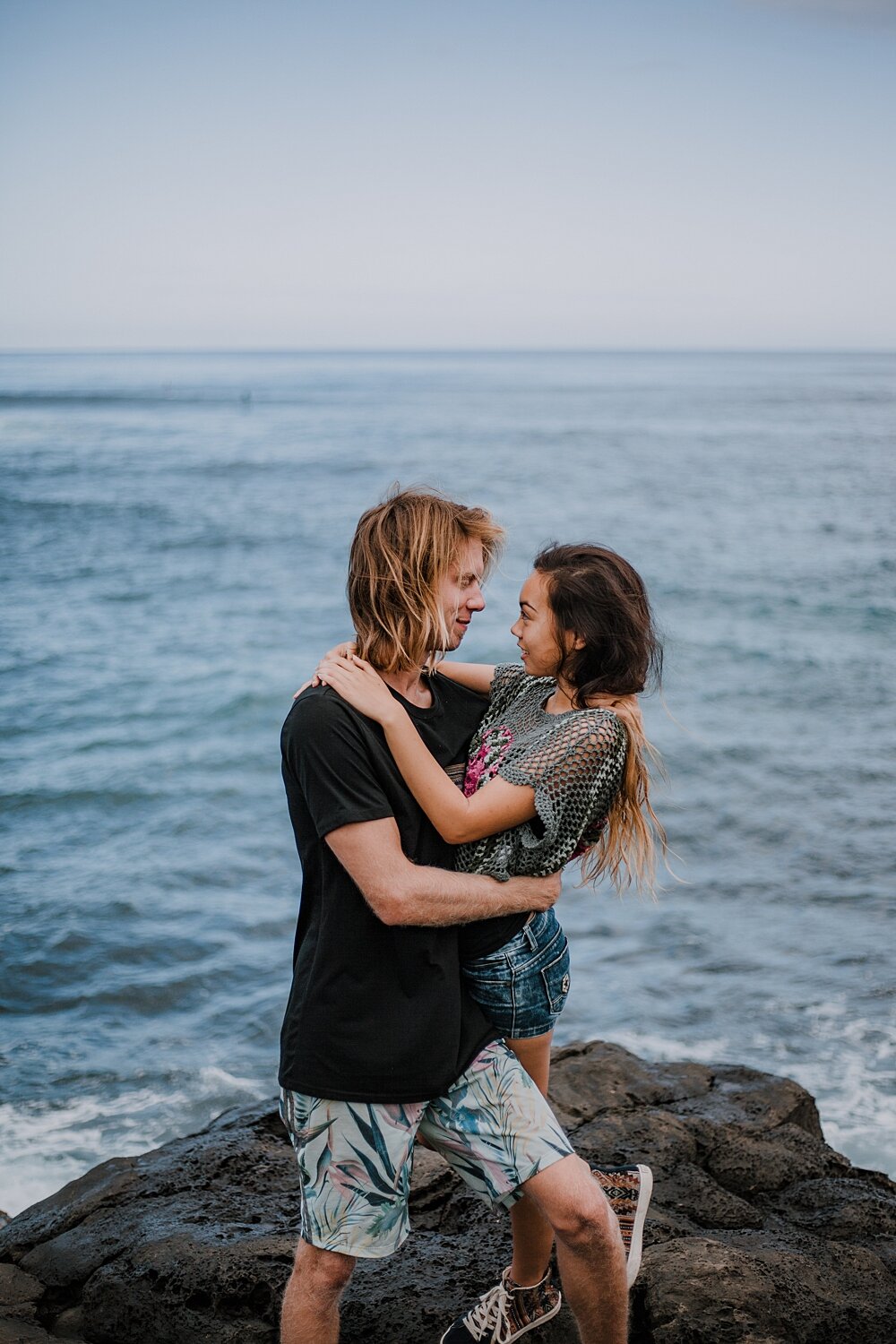 couple standing on lava rocks on ho'okipa beach, couple hiking ho'okipa, maui hawaii photographer, maui hawaii surfing, surfing at ho'okipa beach, ho'okipa beach engagements, motorcycle engagements