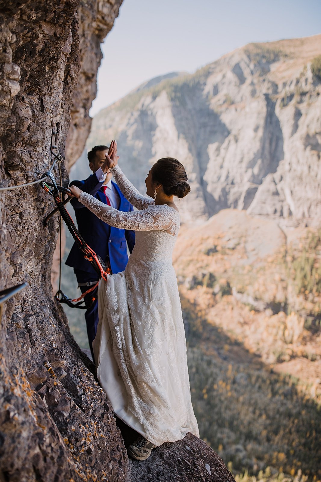 bride and groom high five after climbing past the crux, climbing through telluride's via ferrata main event, climbing elopement in the san juan mountain range of colorado