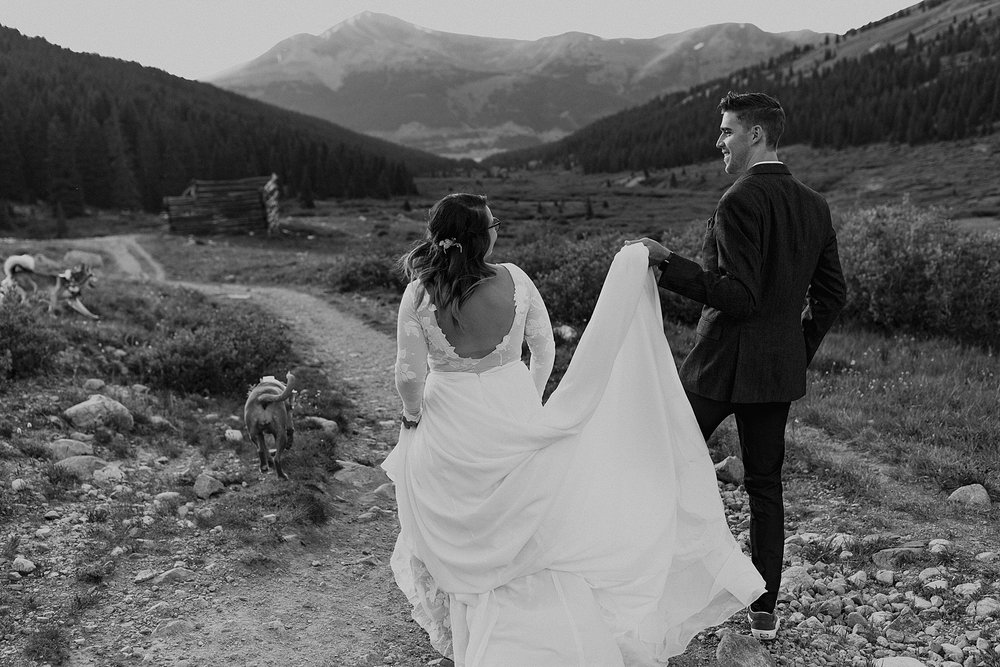 groom helping carry brides skirt, colorado rugged hiking elopement, mayflower gulch elopement, colorado rockies elopement, rocky mountain elopement, leadville colorado elopement