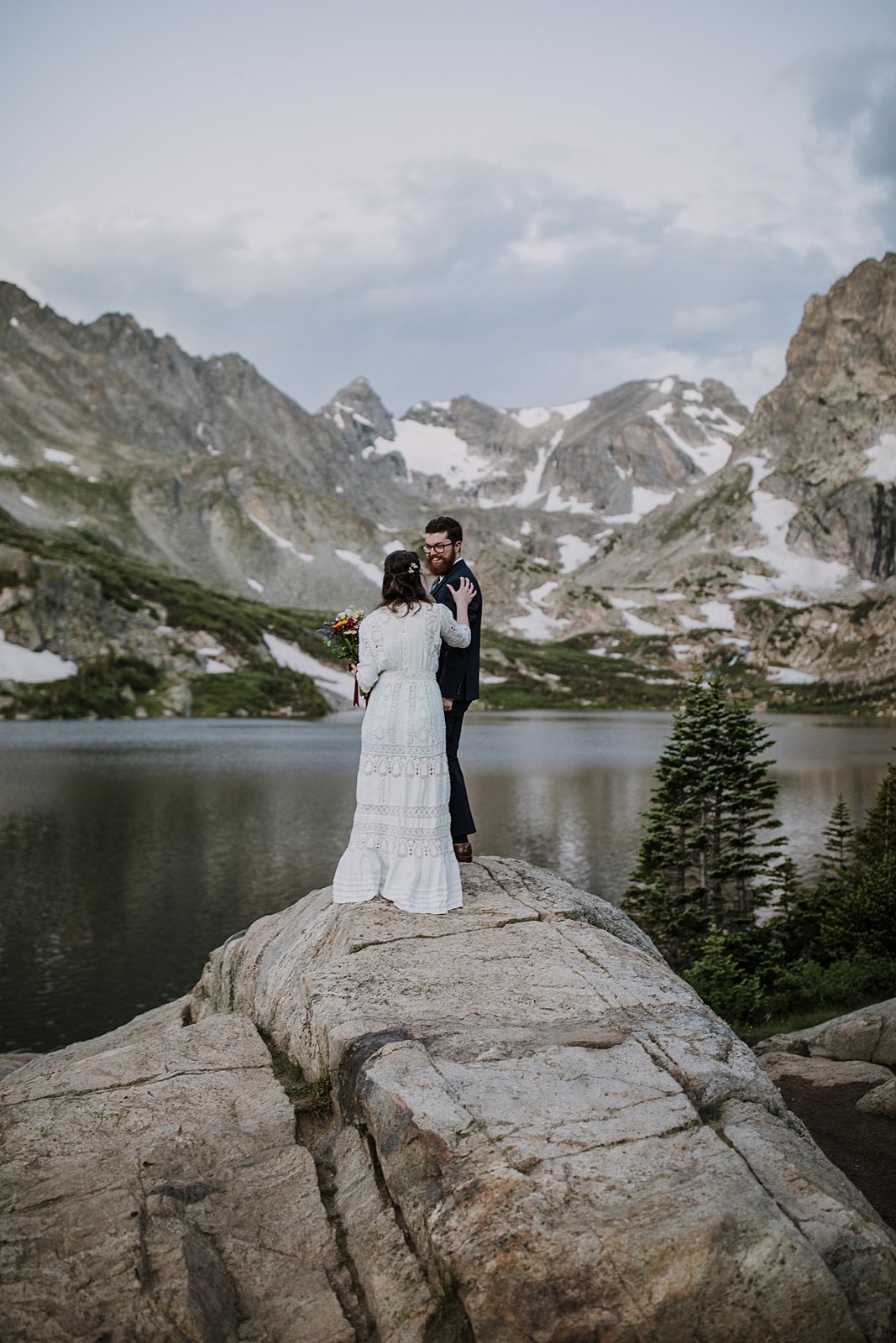 bride and groom elopement first look, bride and groom standing on lake shore, indian peaks wilderness, elopement at lake isabelle, backcountry trekking elopement, glacier valley elopement