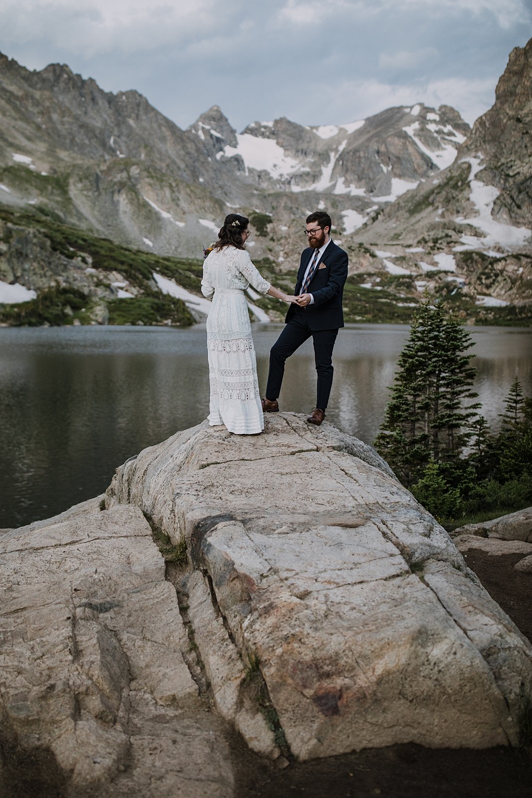 groom looking at brides dress, hiking elopement first look, indian peaks wilderness, elopement at lake isabelle, backcountry trekking elopement, glacier valley elopement