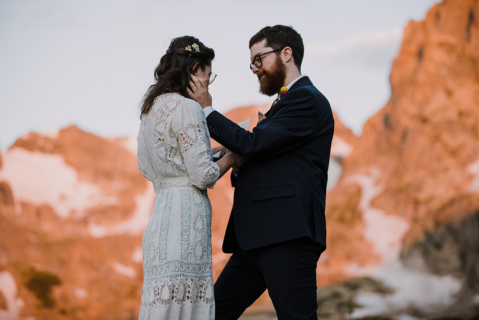 groom wiping away brides tear, colorado mountain alpenglow, sunrise in the indian peaks wilderness, intimate elopement ceremony, rocky mountain sunrise, pink mountains