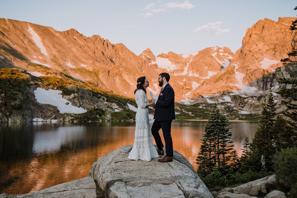 groom sharing his wedding vows, alpenglow reflection on alpine lake, self solemnizing in colorado, self solemnizing ceremony, snow laiden peaks, pine forest elopement