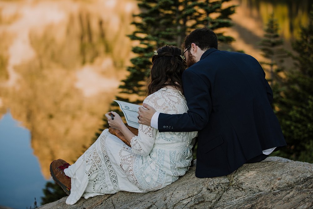 bride and groom signing marriage license on alpine lake shore, calm glass like reflection on lake isabelle, patches of snow on summer mountains, colorado spring snow runoff, pawnee pass alpine lakes 