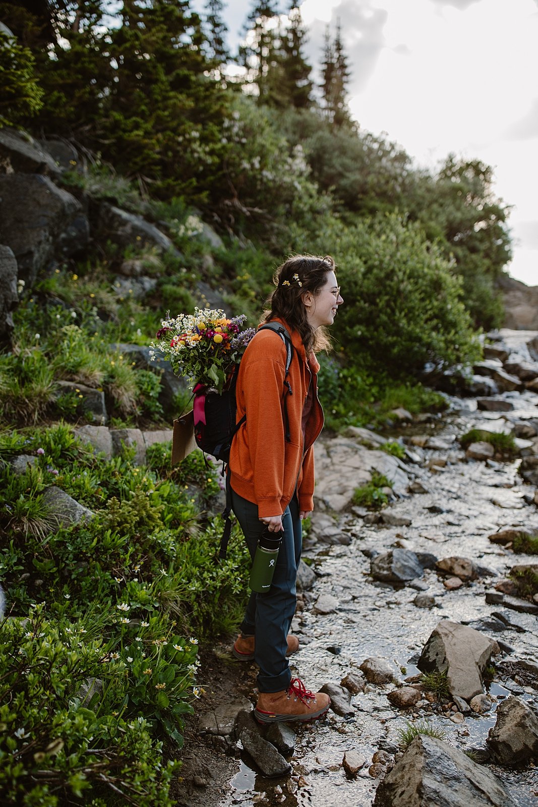 couple hiking down trail, just married handmade elopement signs, pine tree forest, backpacking elopement, high altitude hiking, colorado national forest, wedding bouquet in backpack