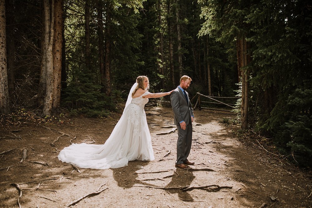 bride taps groom on shoulder for first look, breckenridge mountain wedding, breckenridge nordic center wedding, breckenridge hiking wedding, breckridge trail wedding, summit county colorado wedding