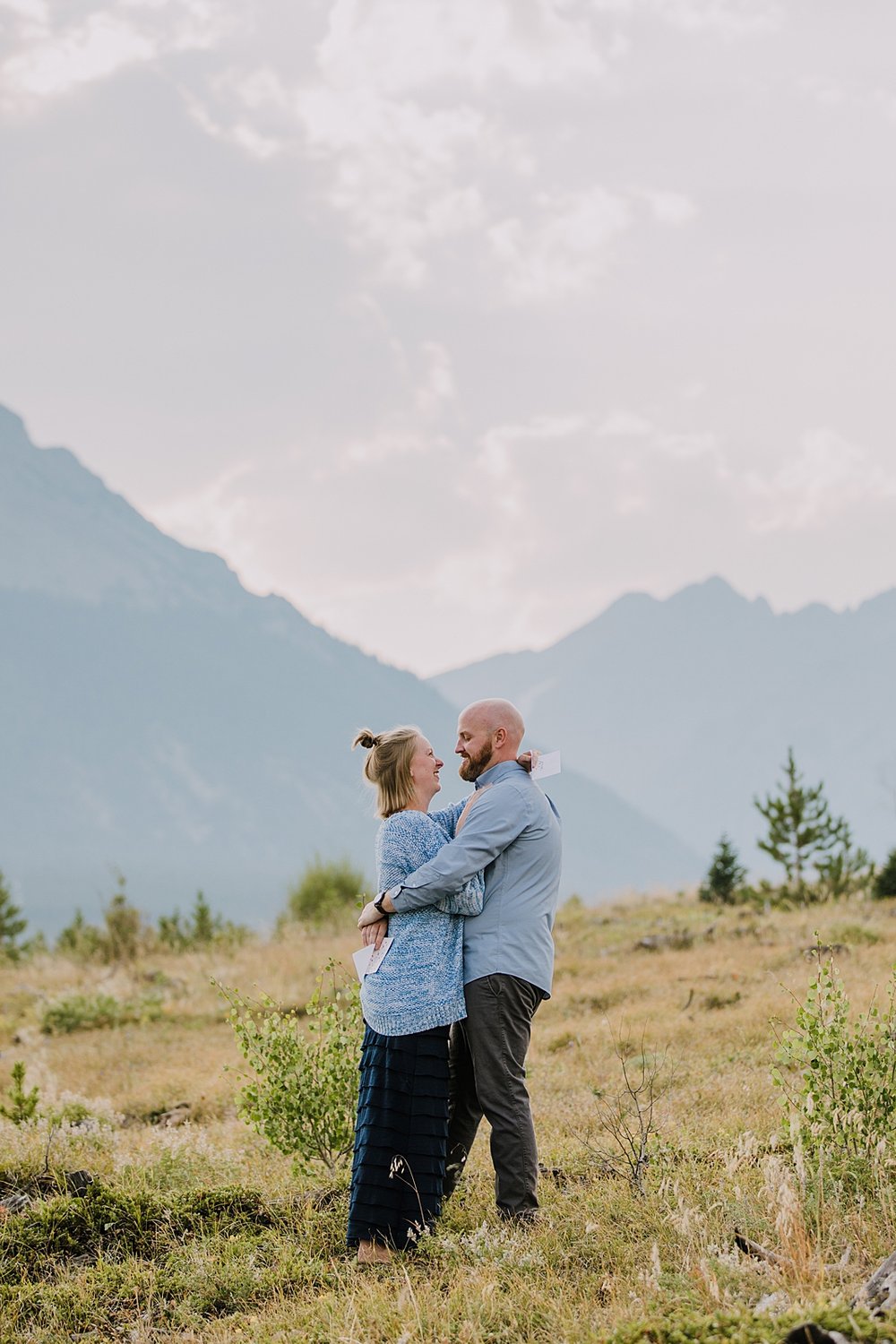 couple reading handwritten letters, postponed wedding ideas, sunset over the gore range, dillon reservoir elopement, silverthorne colorado hiking, silverthorne colorado engagement