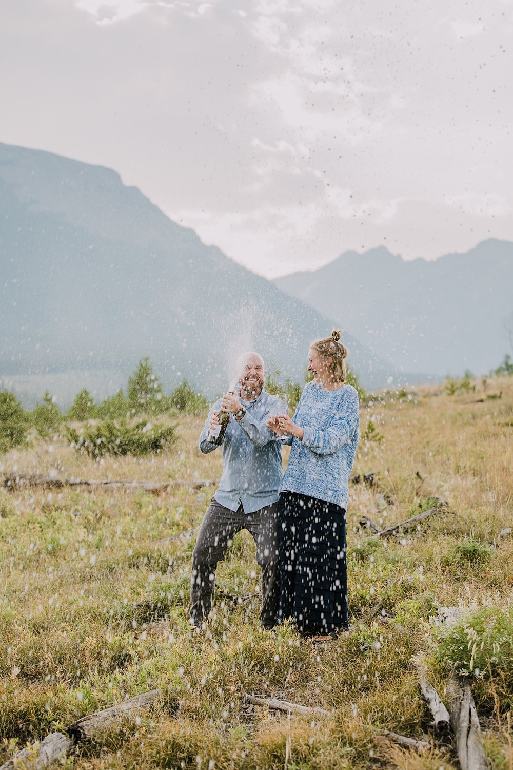 couple popping champagne, champagne mountain toast, elopement champagne toast, champagne spray over the gore mountain range, sunset elopement champagne