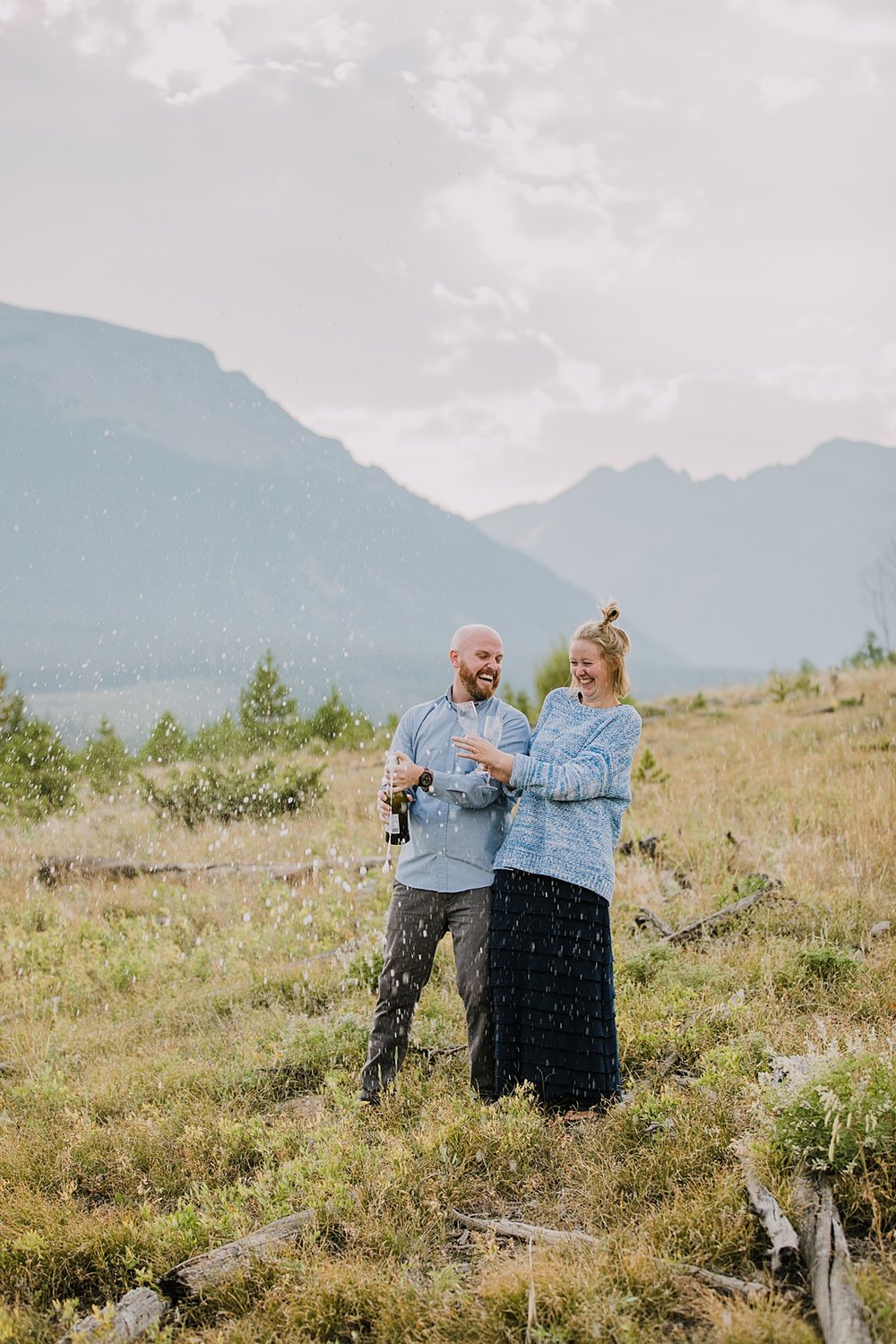 couple popping champagne, champagne mountain toast, elopement champagne toast, champagne spray over the gore mountain range, sunset elopement champagne