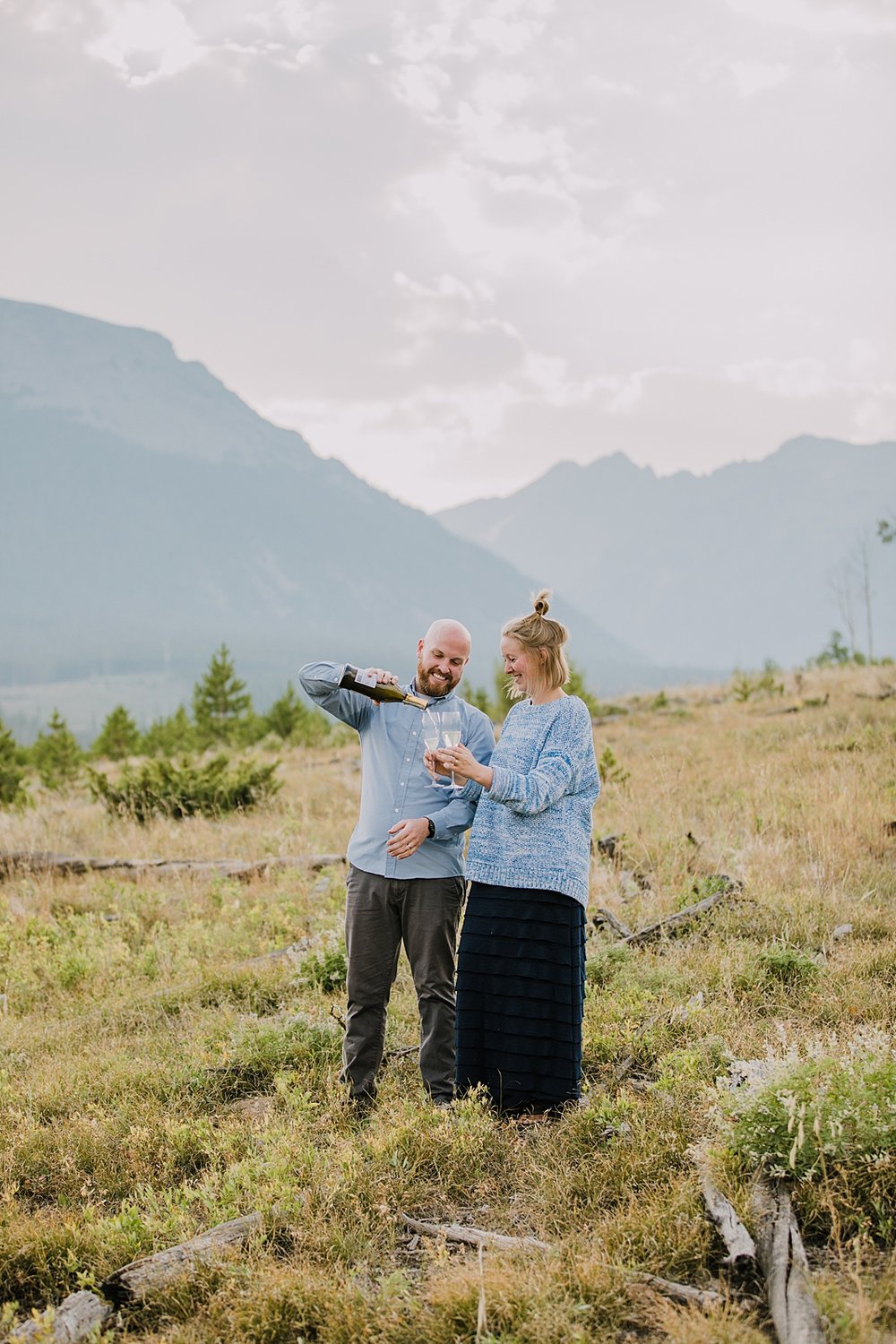 couple popping champagne, champagne mountain toast, elopement champagne toast, champagne spray over the gore mountain range, sunset elopement champagne