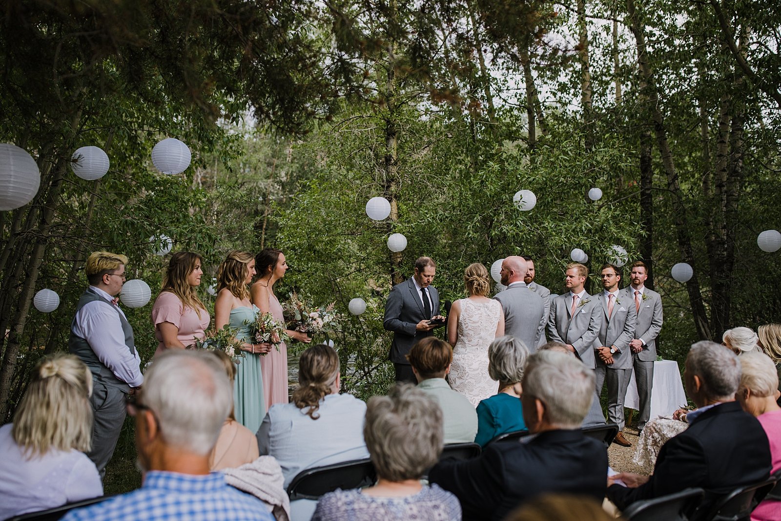 bride and groom listening to officant, silverthorne colorado wedding officiant, paper lantern wedding decor, silverthorne colorado wedding venue, riverside wedding, river bank wedding, river wedding