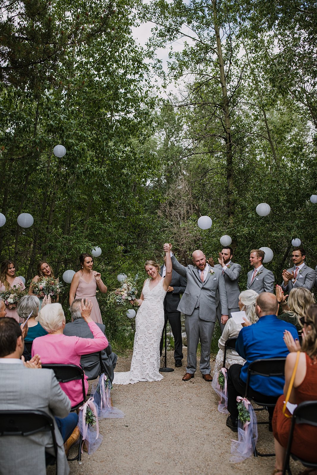 groom raising arm in the air, walking the aisle as husband and wife, silverthorne pavilion wedding ceremony, silverthorne colorado bride, mountain couple, mountain bride, mountain groom