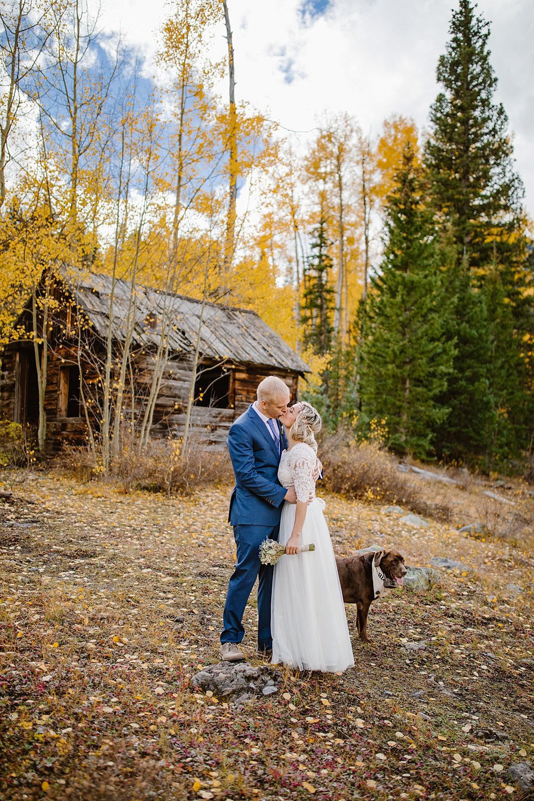 wedding couple with dog in front of a mining cabin, mining cabin elopement, breckenridge mining ruins, colorado fall elopement, boreas pass aspen tunnel, boreas pass elopement, two piece wedding dress