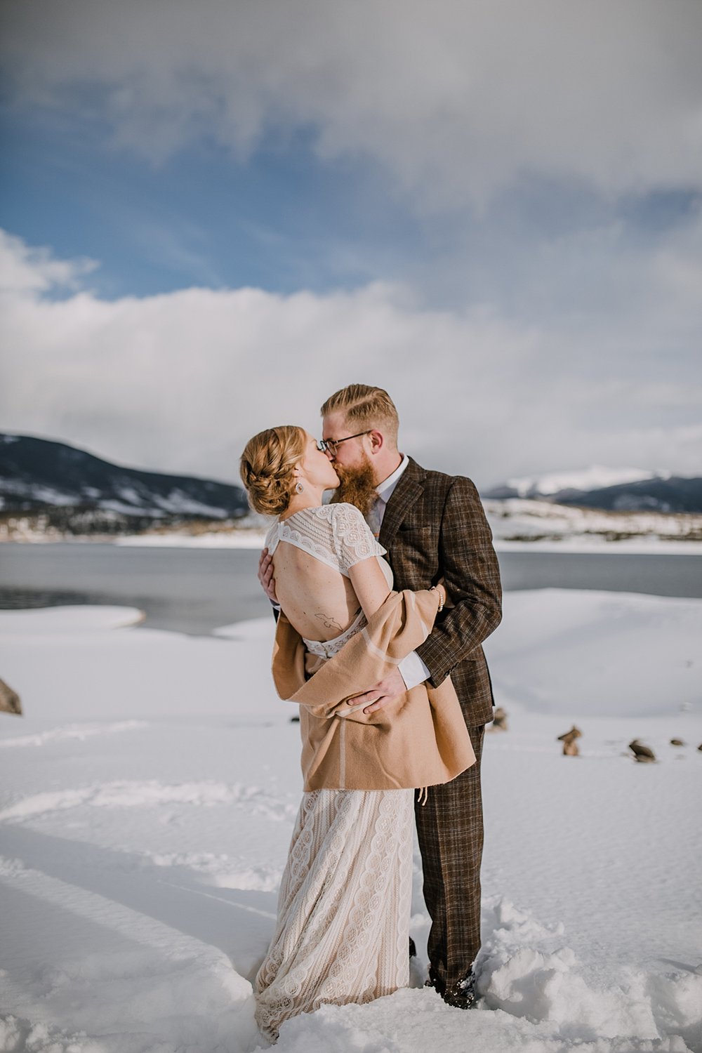 bride and groom kissing in the snow, colorado winter elopement, dillon reservoir winter elopement, snowy breckenridge elopement, breckenridge wedding in the snow, bridal shawl, plaid grooms suit