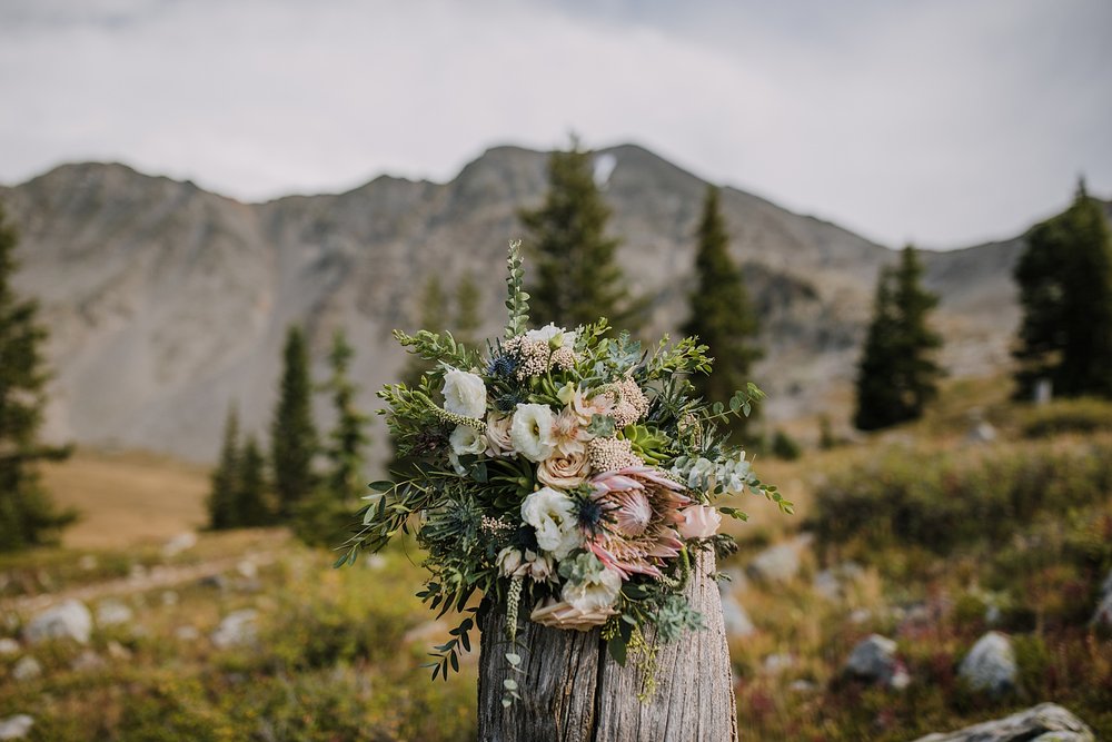 wedding florals sitting on a tree stump, breckenridge nordic center wedding, breckenridge nordic center wedding reception, breckenridge wedding flowers, petal and bean florals, breckenridge flowers