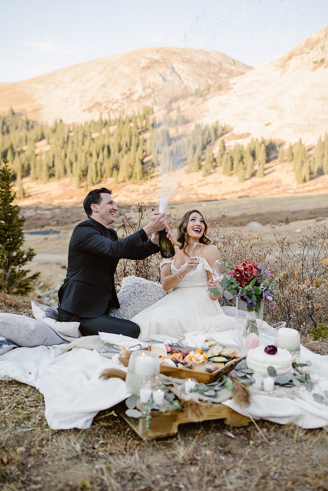 groom popping champagne, bride and groom sharing a drink, hoosier pass elopement, georgia pass elopement, breckenridge charcuterie, breckenridge wedding caterer, breckenridge elopement picnic