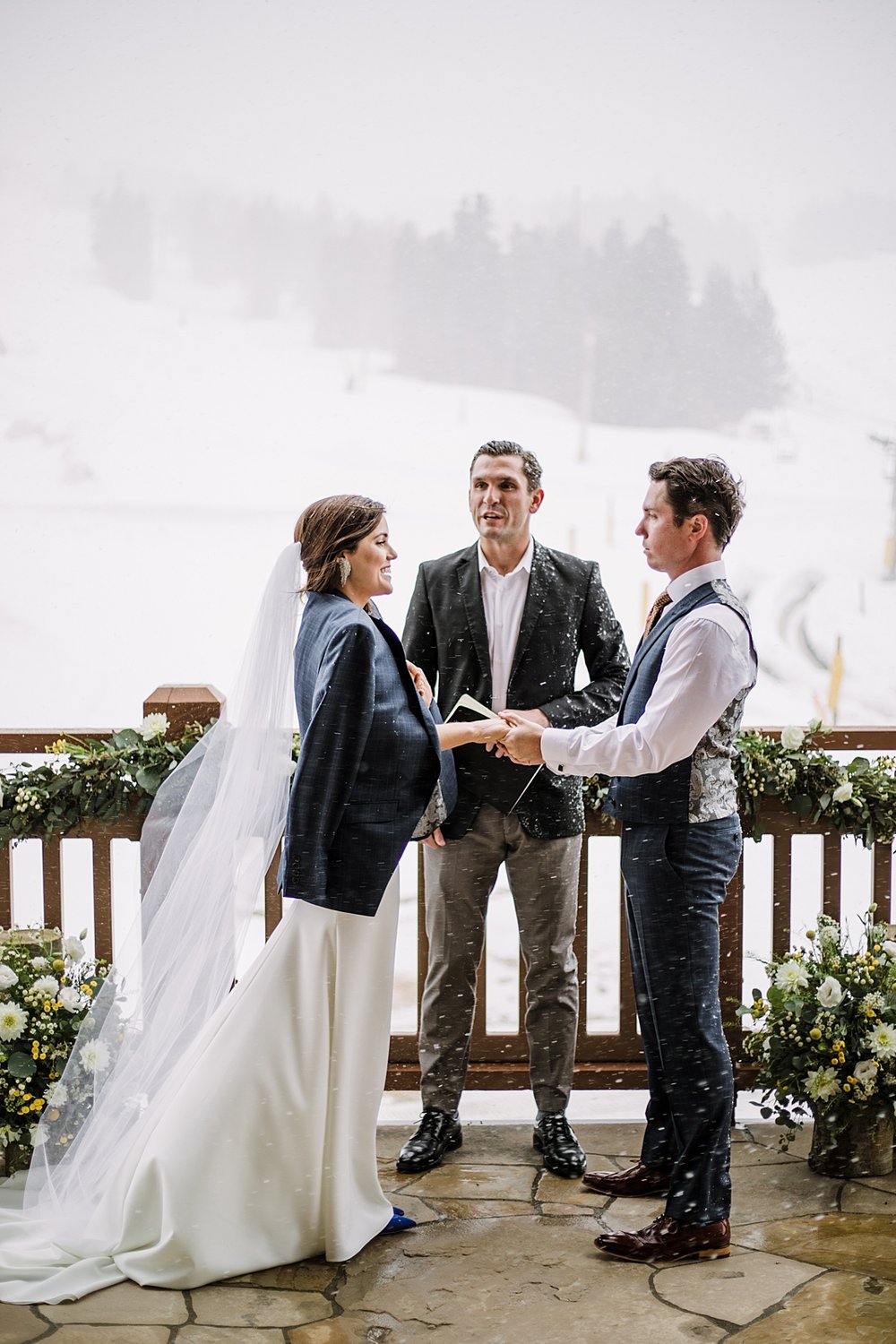 bride and groom sharing vows in the falling snow, groom giving his suit jacket to the bride, snowy wedding ceremony, sevens wedding, breckenridge sevens wedding, peak 8 wedding, blue wedding shoes