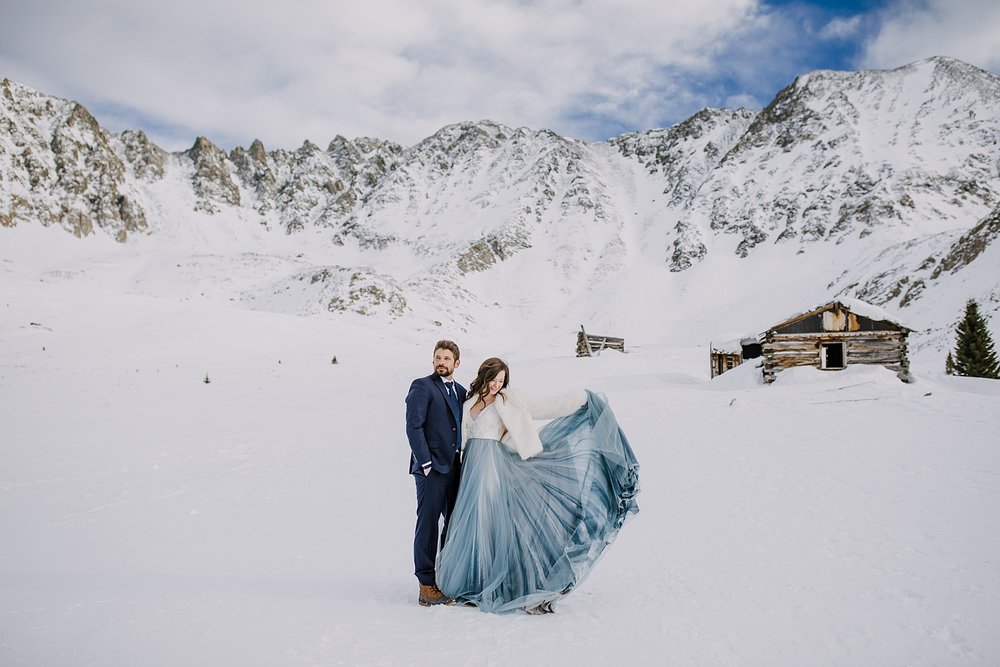 bride throwing wedding dress train, bride and groom in front of mountain range, tenmile elopement, breckenridge winter elopement, snowy breckenridge elopement, snowy mountain elopement