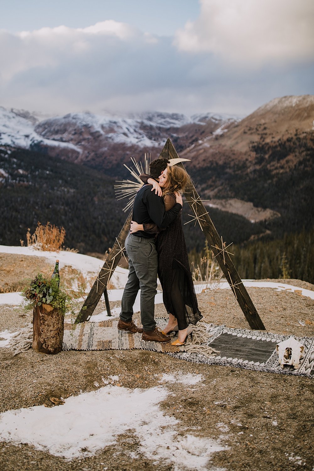 bride and groom hugging at the alter, moody elopement, moody wedding, antler wedding decor, triangle wedding arch, triangle ceremony arch, triangle elopement arch, dark wedding dress