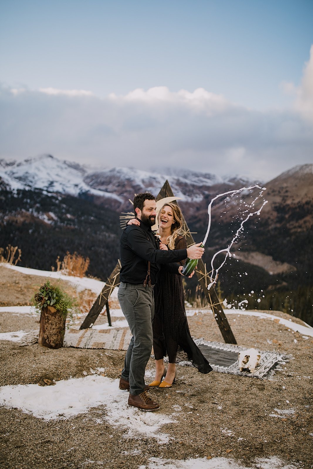 couple popping champagne, mountain top elopement, mountain top ceremony, high alpine mountain pass elopement, high alpine mountain pass wedding ceremony, mountain peak ceremony, black wedding dress
