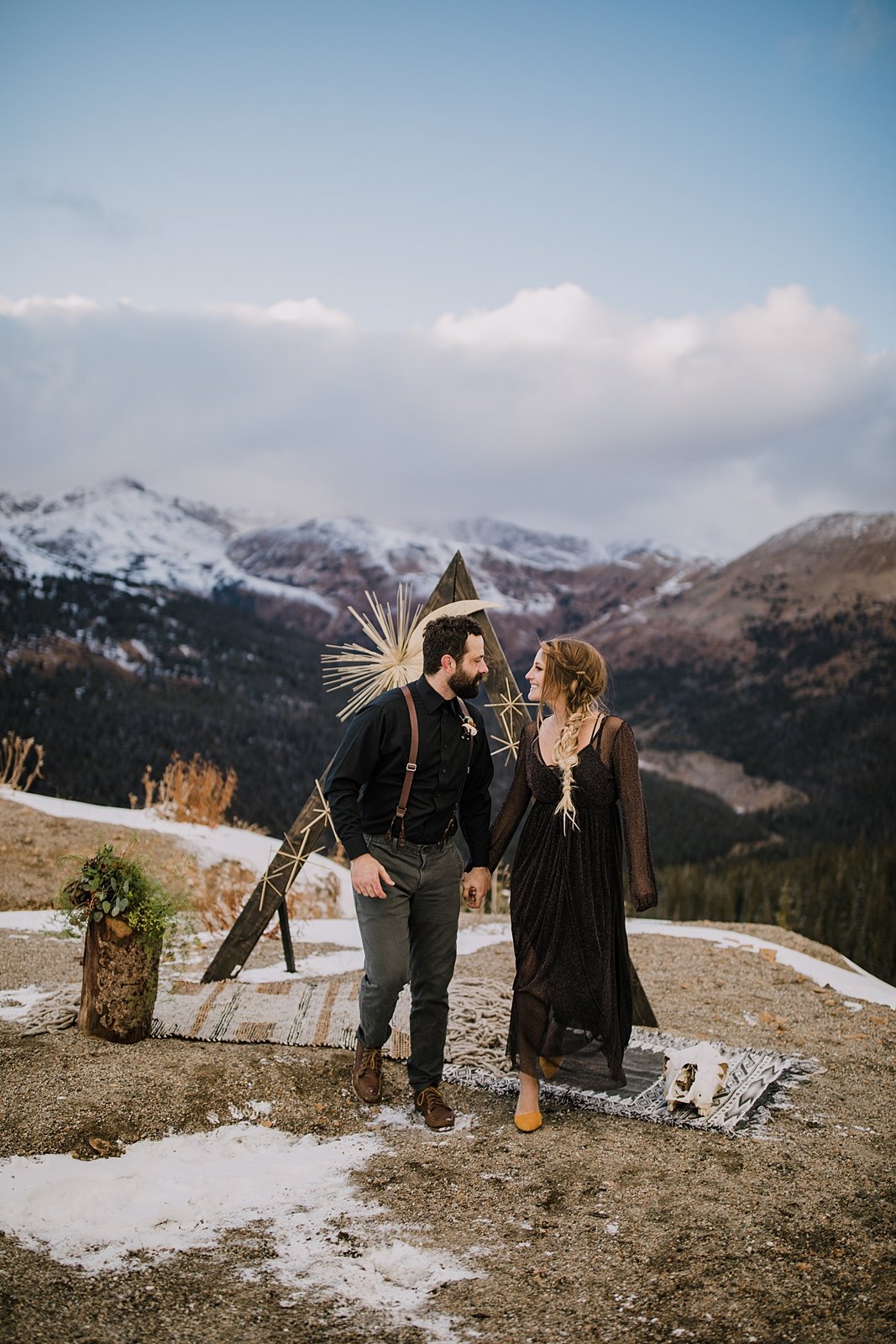 bride and groom walking down the aisle, snow capped mountain elopement, moody elopement, moody wedding, antler wedding decor, triangle wedding arch, triangle ceremony arch, triangle elopement arch