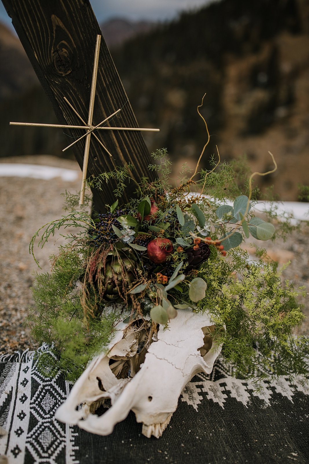 terrestrial wedding decor at the base of the arch, taxidermy wedding decorations, cattle skull wedding decor, animal skull wedding decor, florals with pomegranates, dried fruit and berry fall florals