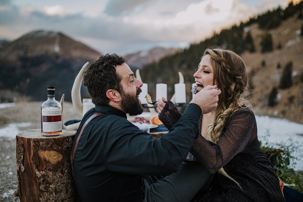 couple eating wedding cake, witchy wedding cake, til death wedding cake, celestial themed wedding table, celestial wedding decorations, celestial wedding inspiration, wood table bridal picnic