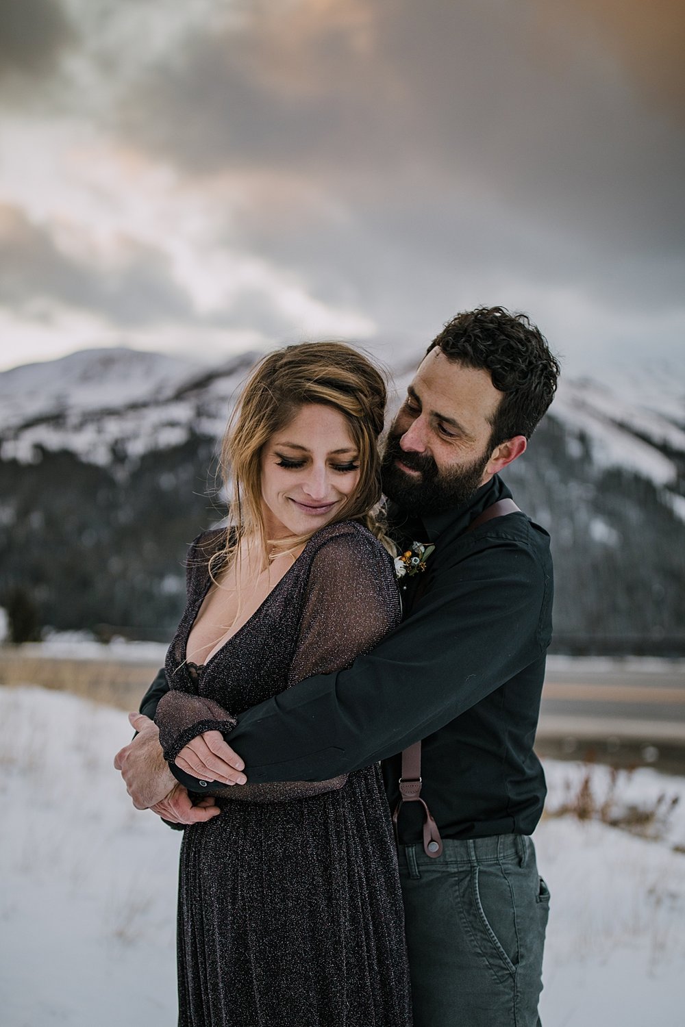 groom holding bride close, black bridal attire, bride and groom in black wedding attire, stormy mountain elopement, celestial inspired mountain pass elopement, moon and stars inspired wedding