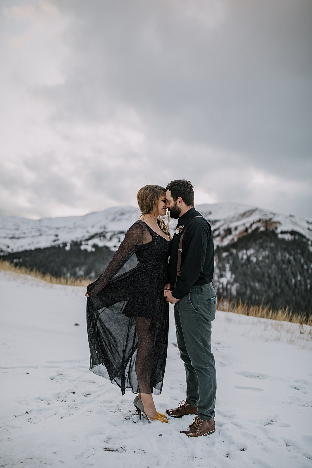 bride tossing wedding dress in the wind, snowy fall mountain elopement, stormy mountain elopement, celestial inspired mountain pass elopement, high alpine fall mountain elopement, summit vow ceremony