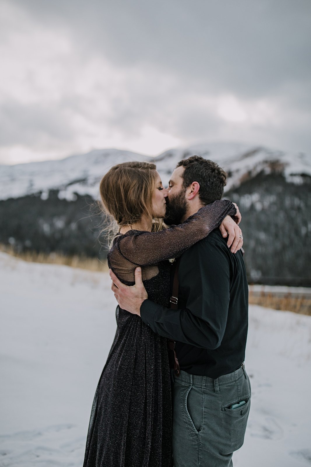 bride and groom holding one another close and kissing, continental divide elopement, continental divide wedding, celestial elopement, celestial wedding, snowy mountain peak wedding backdrop
