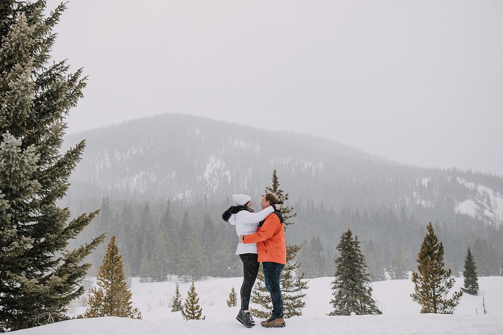 woman says yes to proposal, snowshoe proposal, snowy mountain proposal, breckenridge proposal, swan river valley winter activities, sleigh ride proposal, white winter brides jacket, pine tree proposal