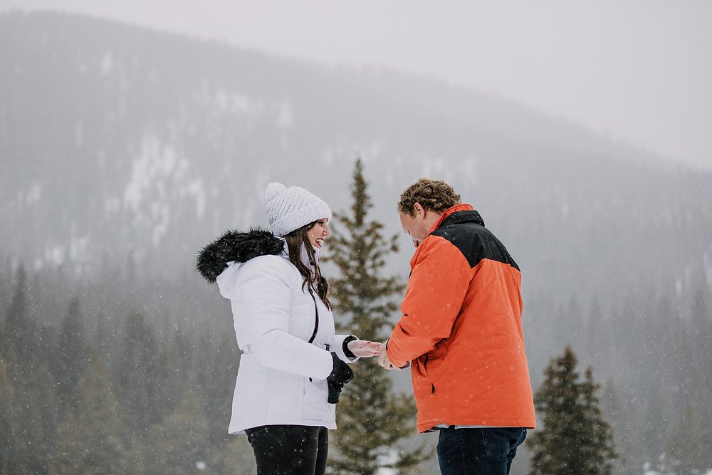 man putting ring on girls finger, summit county proposal, summit county winter proposal, colorado winter wedding, breckenridge winter wedding, summit county sleigh rides, engagement ring