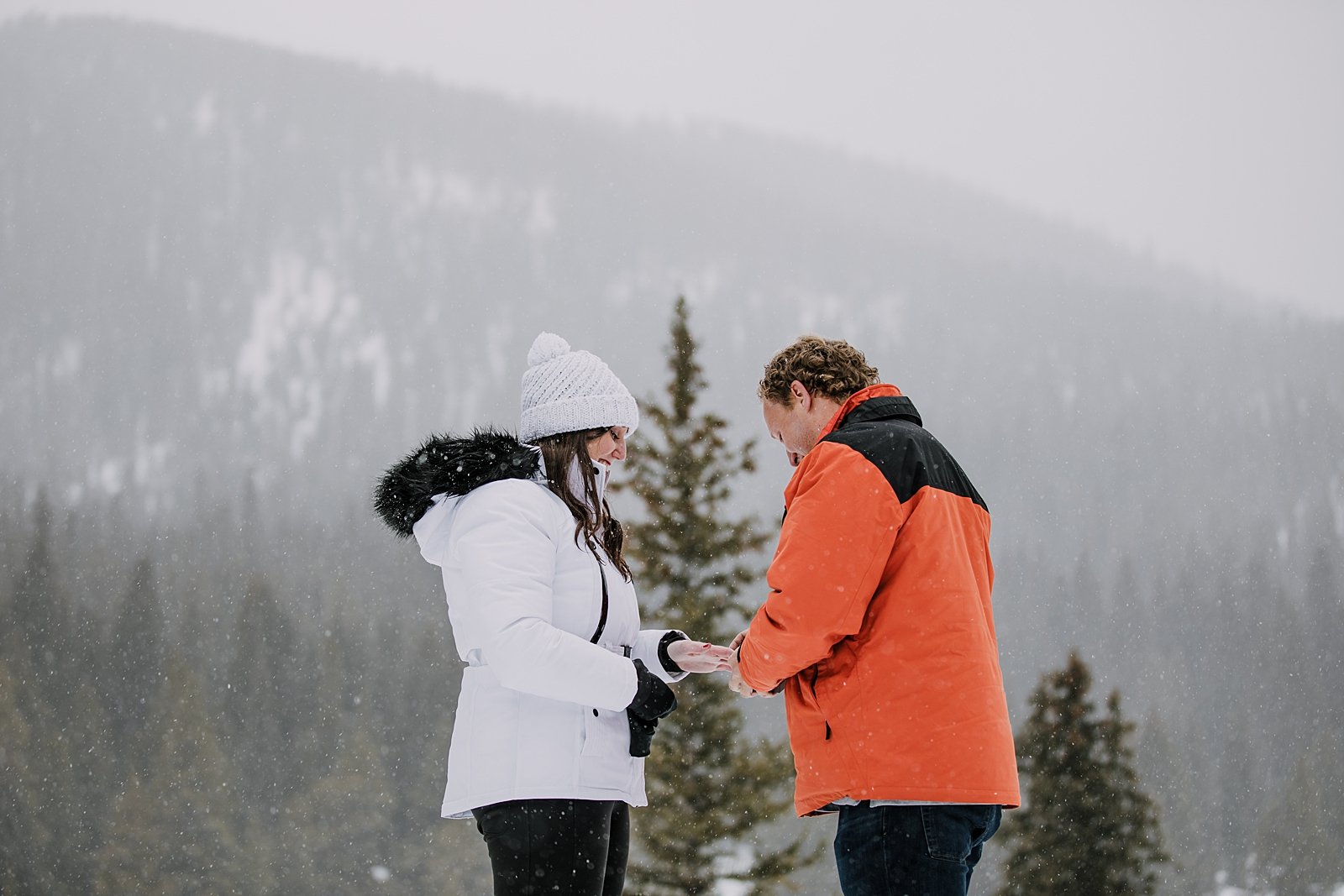 man putting ring on girls finger, summit county proposal, summit county winter proposal, colorado winter wedding, breckenridge winter wedding, summit county sleigh rides, snowy engagement