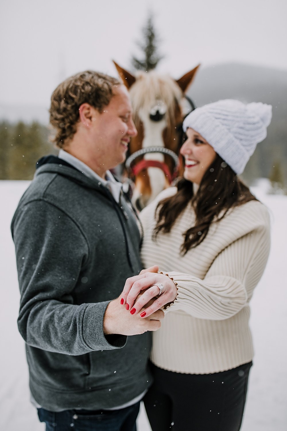 couple holding hands and showing off engagement ring, golden horseshoe private sleigh ride, red proposal nails, red wedding nails, breckenridge elopement photographer, summit county photographer