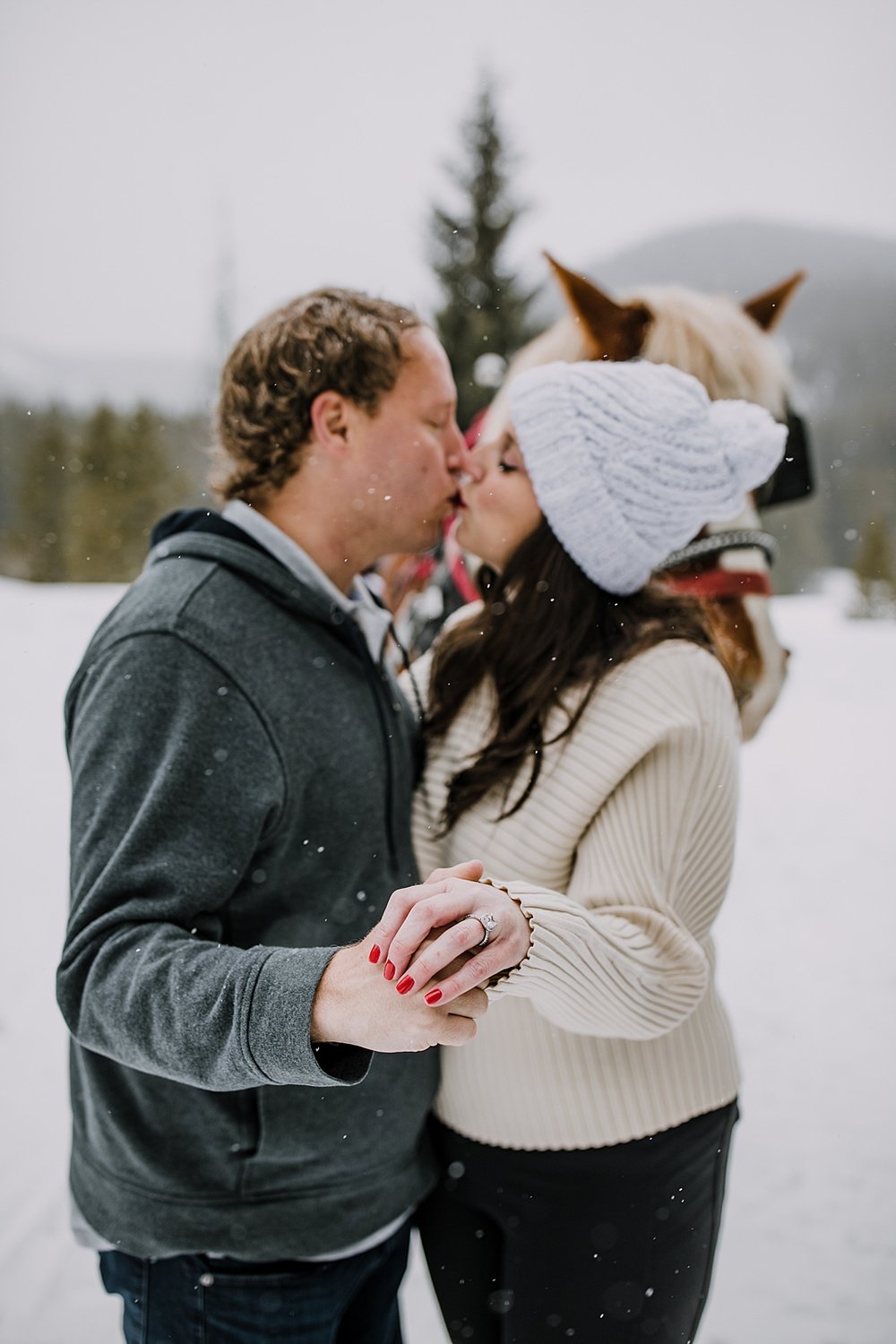 couple kissing and showing off engagement ring, golden horseshoe private sleigh ride, red proposal nails, red wedding nails, breckenridge elopement photographer, summit county elopement photographer