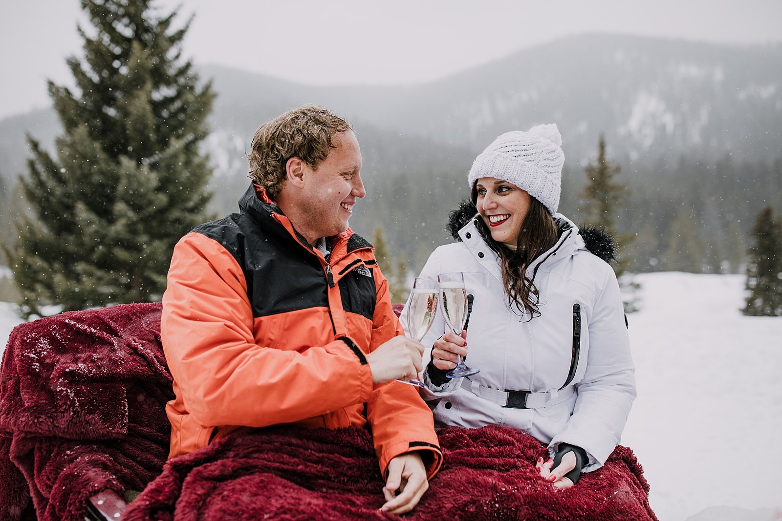 couple toasting champagne on a one horse open sleigh in the woods, open one horse sleigh gliding through the snow, breckenridge spring break proposal, winter bridal jacket, winter bridal attire