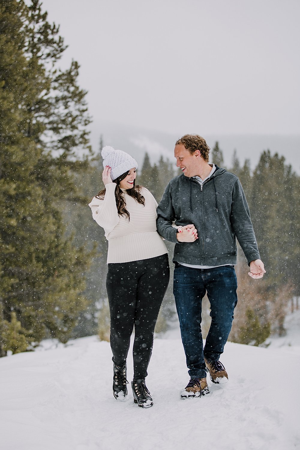 couple holding hands and laughing, engagement ring in the snow, summit county winter engagement, breckenridge winter engagement, colorado winter engagement, leadville winter engagement