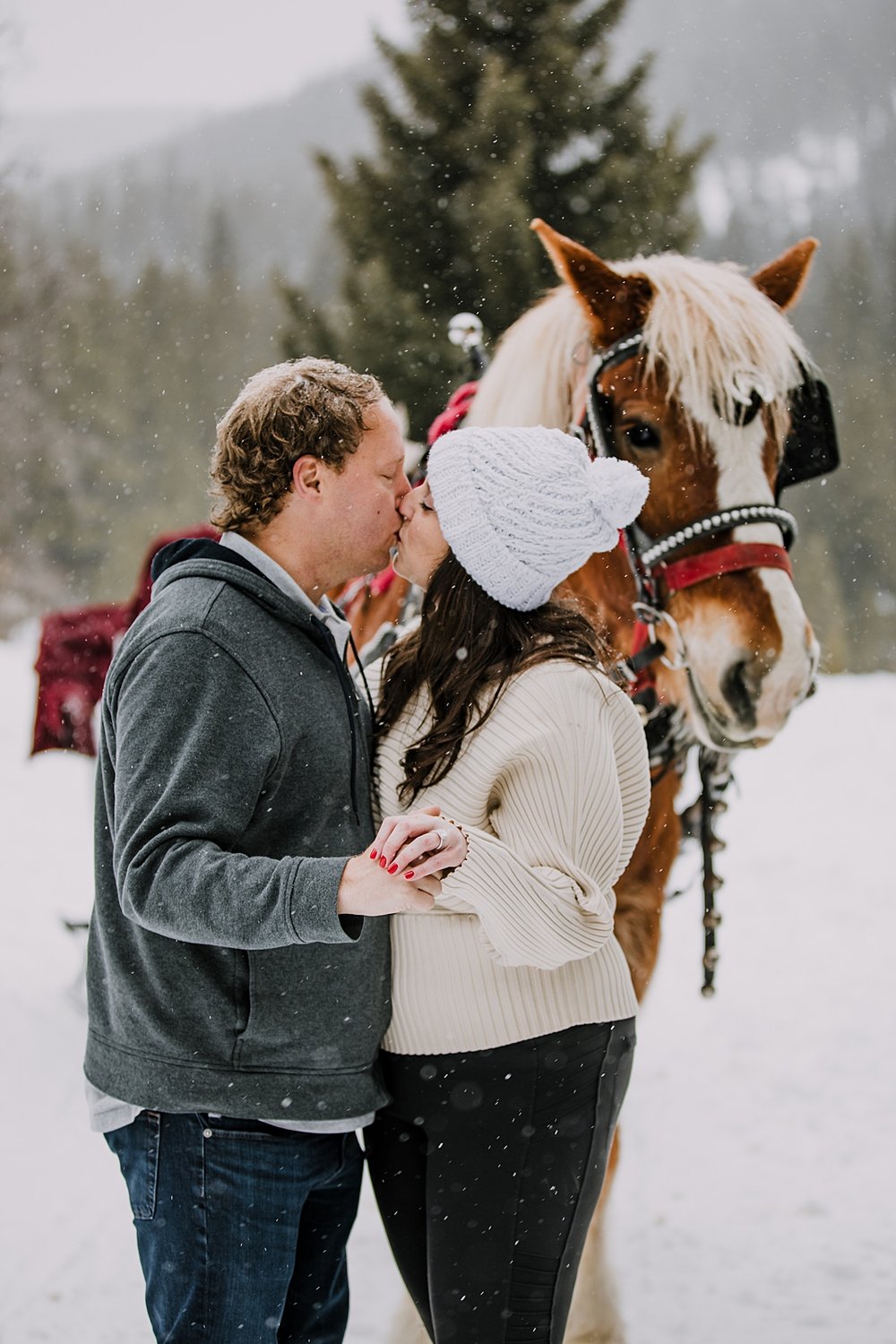 couple kissing and showing off engagement ring, golden horseshoe private sleigh ride, red proposal nails, red wedding nails, breckenridge elopement photographer, summit county elopement photographer