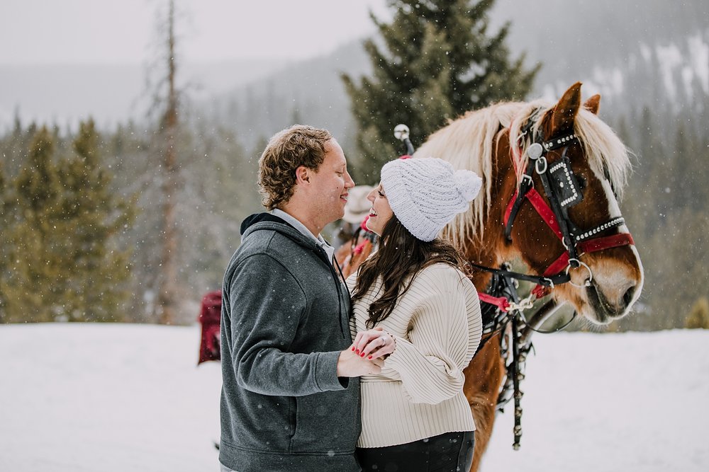 couple standing in front of horse, one horse open sleigh, colorado sleigh ride, breckenridge sleigh ride, summit county sleigh ride, percheron draft horse, colorado winter elopement photographer