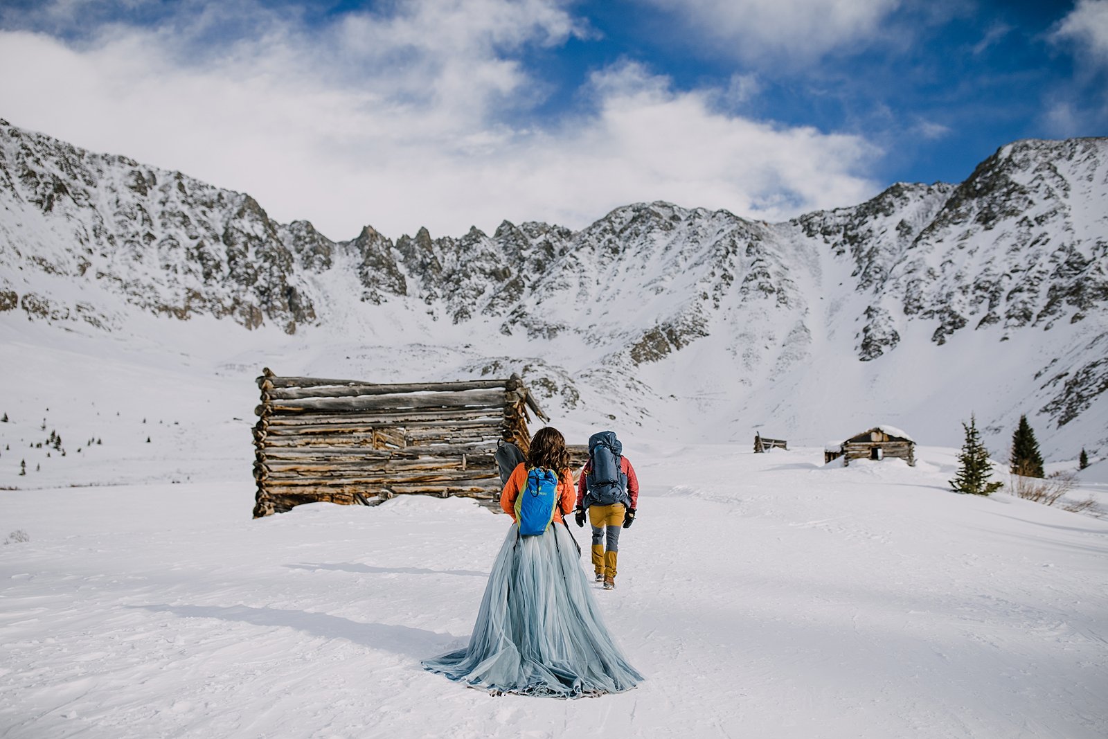 couple hiking into snow laden valley, winter backpacking elopement, snowy mountain elopement, breckenridge winter elopement, emma and grace bridal wedding dress, mining cabin elopement