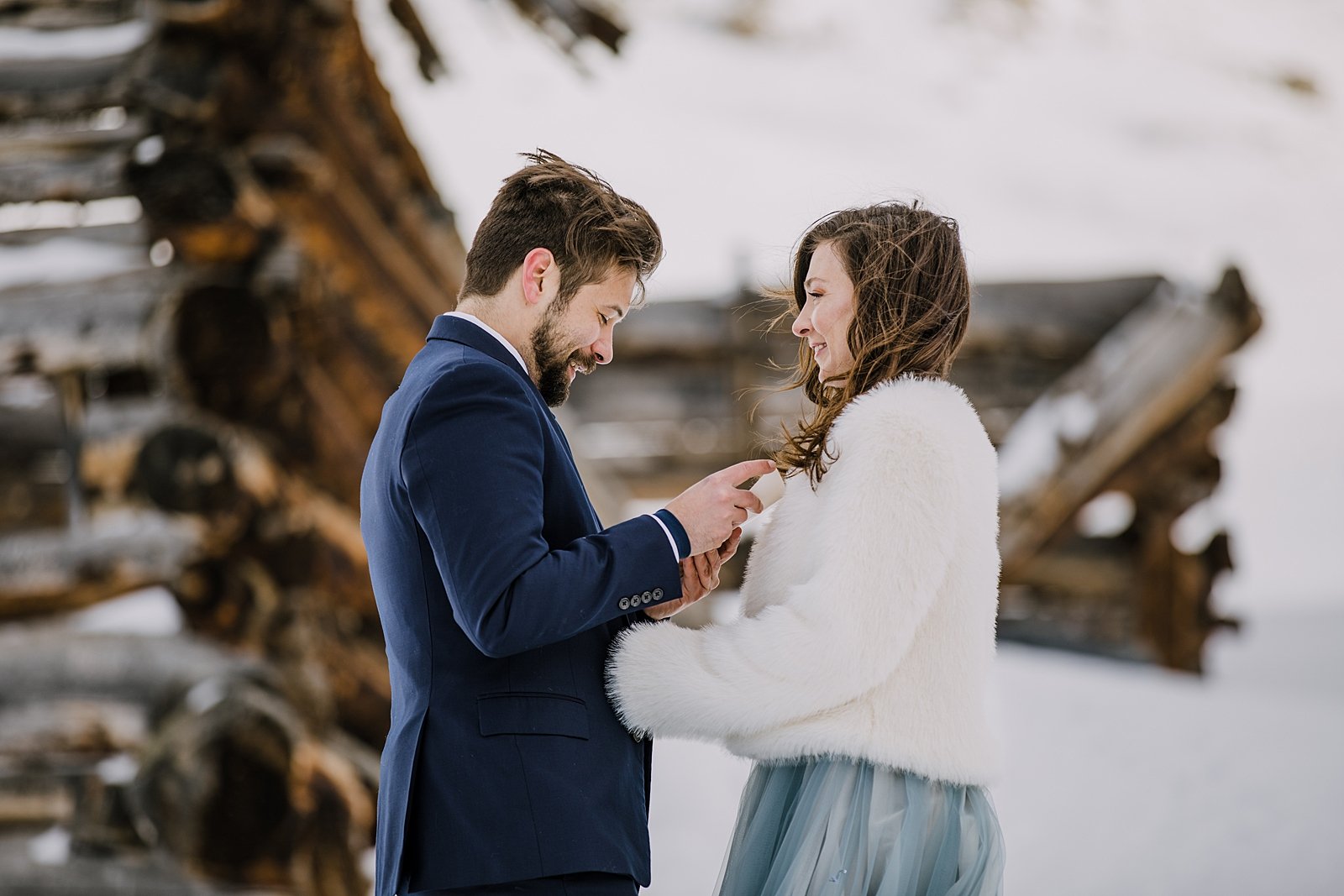 bride and groom laughing during vows, white fur jacket for winter wedding, blue tux for wedding, breckenridge winter wedding, leadville winter wedding